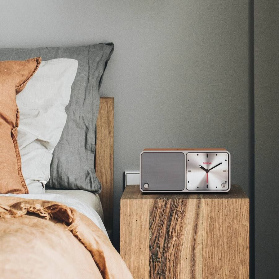 A Geneva Time analogue clock radio on a hotel nightstand