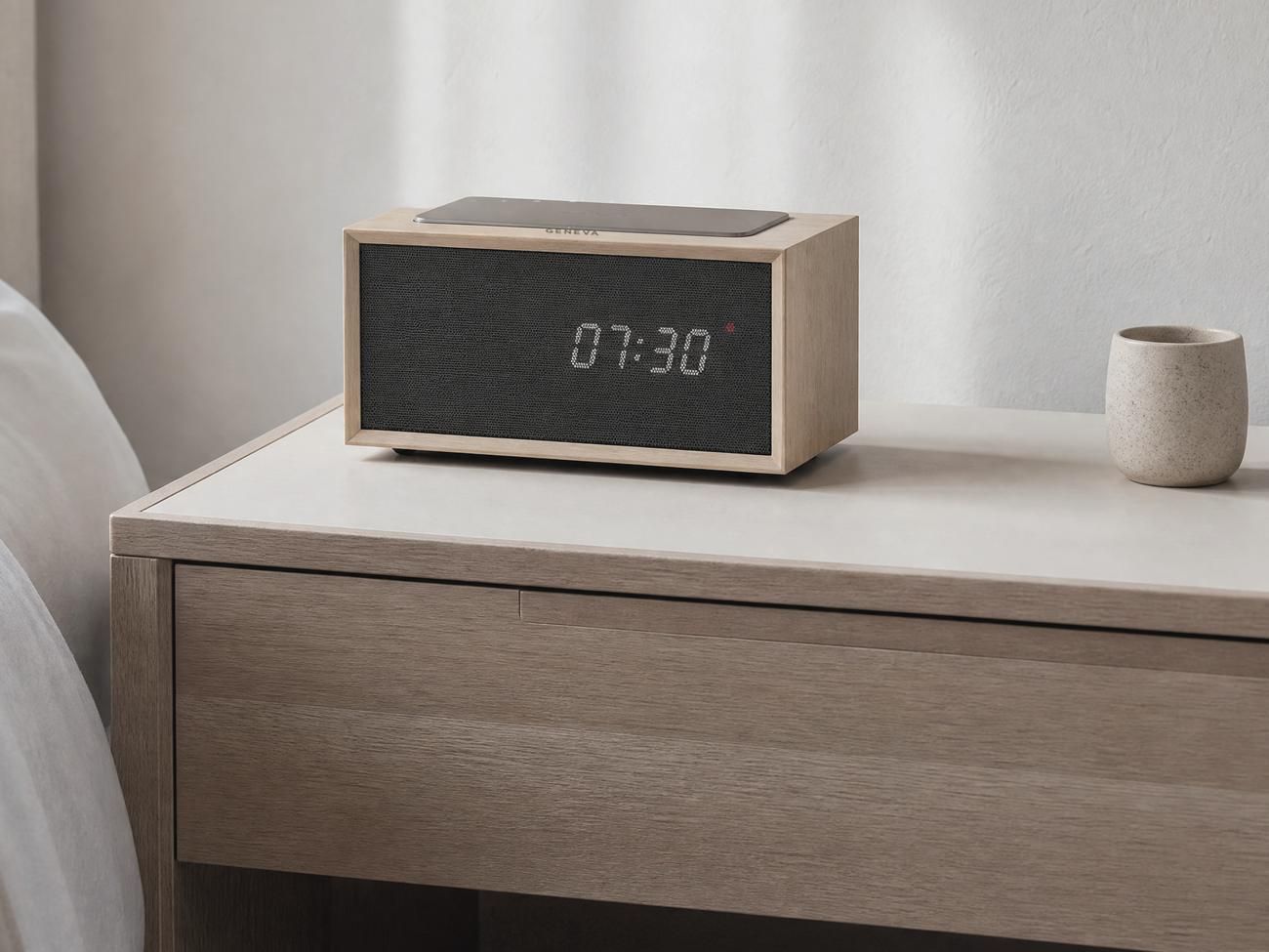 A Geneva Time digital in oak on a bedside table in a daylit guest room