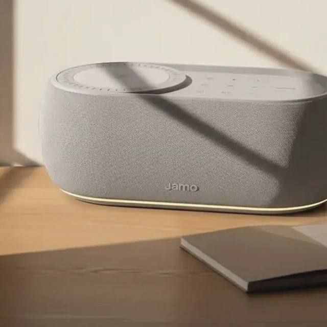 A Jamo HYG Reflect in light grey textile on an oak surface