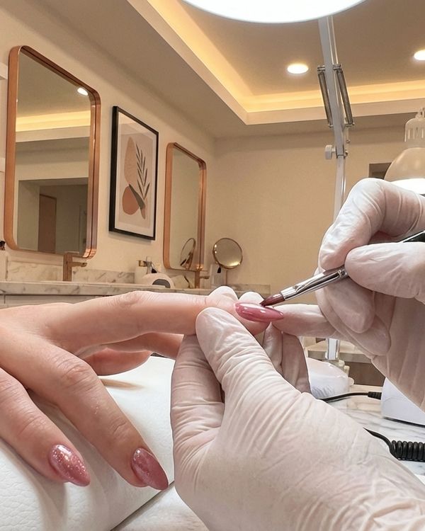 Nail technician carefully painting a client's nails at Bliss Nails & Spa
