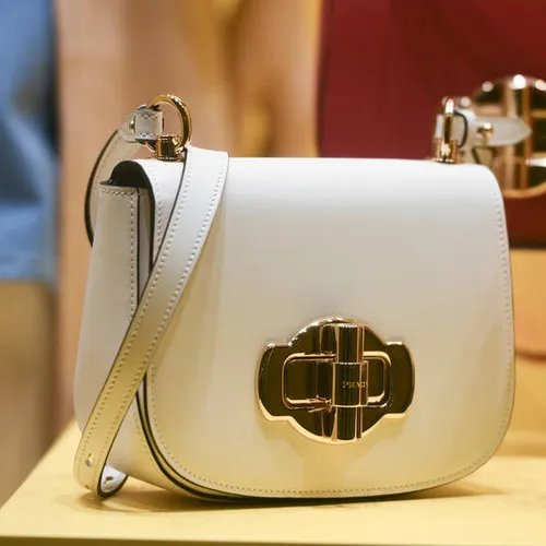 กระเป๋า Prada สีขาวครีมวางบนชั้นโชว์