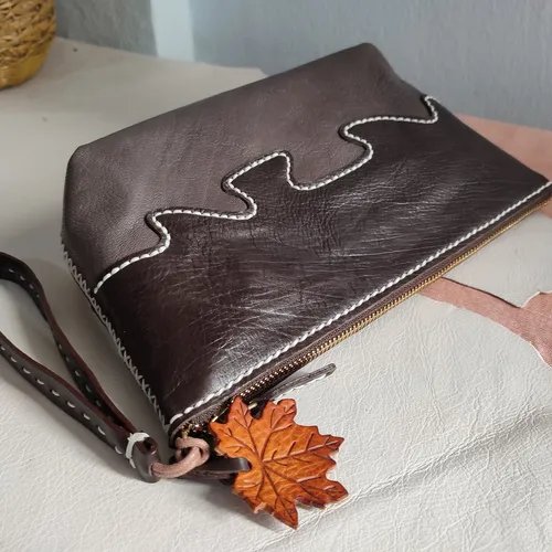 กระเป๋าคลัตช์หนังสีน้ำตาลสองโทน เย็บลายคลื่นสีขาว พร้อมสายคล้องมือและจี้ใบเมเปิล