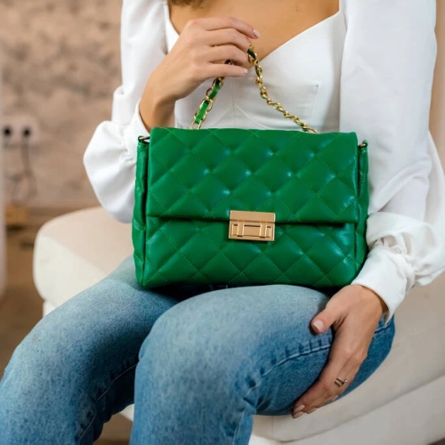 สุภาพสตรีถือกระเป๋าสะพายสีเขียวมรกตลายควิลท์ ประดับสายโซ่และตัวล็อกสีทอง