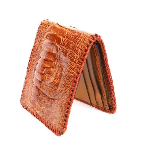 กระเป๋าสตางค์หนังนกกระจอกเทศสีน้ำตาลส้มที่มีพื้นผิวเป็นปุ่มนูนชัดเจนและเย็บขอบด้วยด้ายสีส้มแดง วางเปิดเล็กน้อย