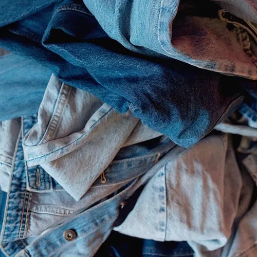 กองผ้าเดนิมสีน้ำเงินหลากหลายเฉดพับรวมกัน