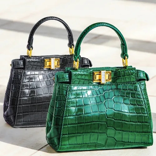 กระเป๋าถือหนังลายจระเข้สีเขียวและสีดำประดับอะไหล่ทองทรงสี่เหลี่ยมวางคู่กัน