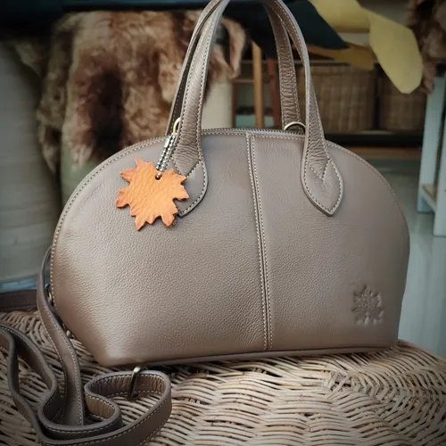 กระเป๋าถือหนังแท้สีเทาอมน้ำตาลทรงโดมพร้อมสายสะพาย สะท้อนความสวยงามที่ปรับใช้ได้หลายโอกาส