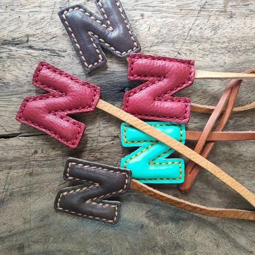 ที่ห้อยกระเป๋า N หนังแท้สีน้ำตาลเข้ม แขวนอยู่บนหูกระเป๋าถือของผู้หญิง