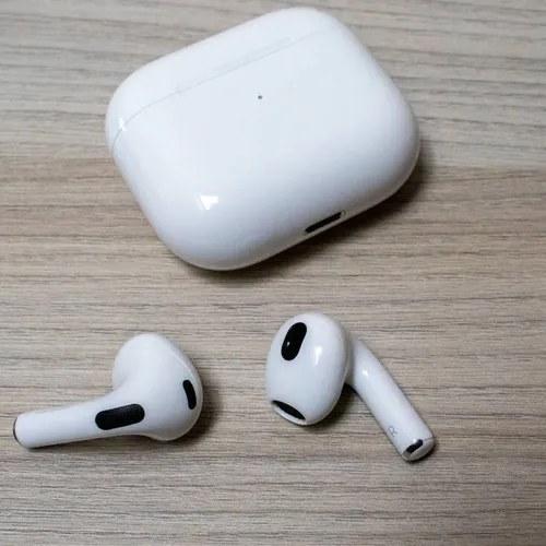 หูฟังไร้สาย Apple AirPods สีขาว พร้อมเคสชาร์จ วางอยู่บนพื้นไม้สีอ่อน