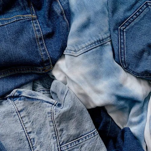 กางเกงยีนส์หลากหลายเฉดสีพับกองรวมกัน