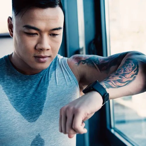 ชายหนุ่มมีรอยสักกำลังออกกำลังกายในยิม