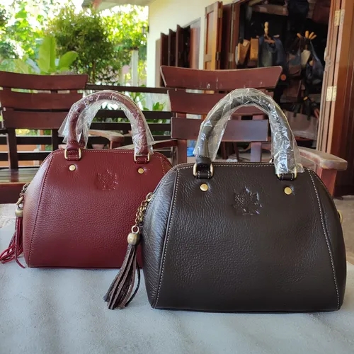 กระเป๋าสะพายหนังสีแดงและน้ำตาลสำหรับใส่ของใช้ส่วนตัว