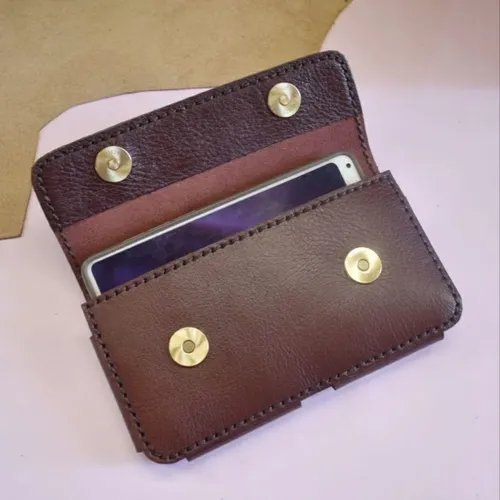 กระเป๋าหนังสีน้ำตาลเข้มใส่โทรศัพท์มือถือ เปิดอ้าเล็กน้อย เผยให้เห็นโทรศัพท์ด้านใน มีกระดุมแม่เหล็กทองเหลือง 4 จุด