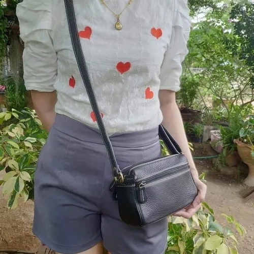 หญิงสาวสะพายกระเป๋าครอสบอดี้สีดำในลุคสบายๆ