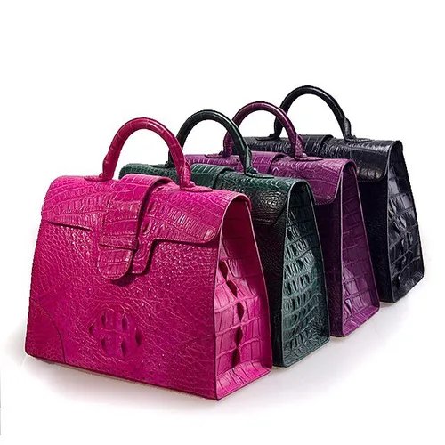 กระเป๋าหนังจระเข้สี่ใบสีชมพู เขียว ม่วง และดำ วางเรียงกันบนพื้นหลังสีขาว