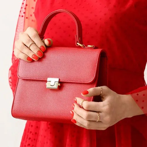 ผู้หญิงถือกระเป๋าสีแดงพร้อมเครื่องประดับสีทอง