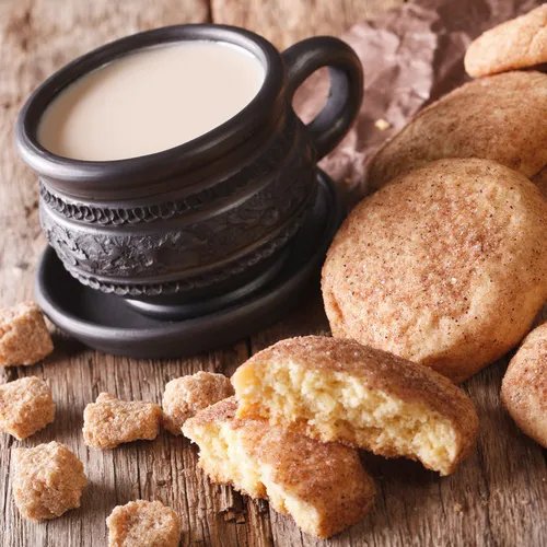 แก้วเครื่องดื่มสีดำพร้อมคุกกี้วางบนพื้นไม้