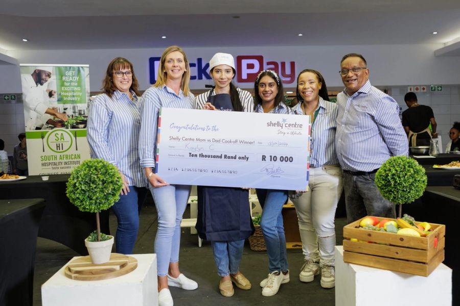Shelly Centre team and cook-off winners holding a large prize cheque at the Shelly Centre Cook-Off, Shelly Beach.