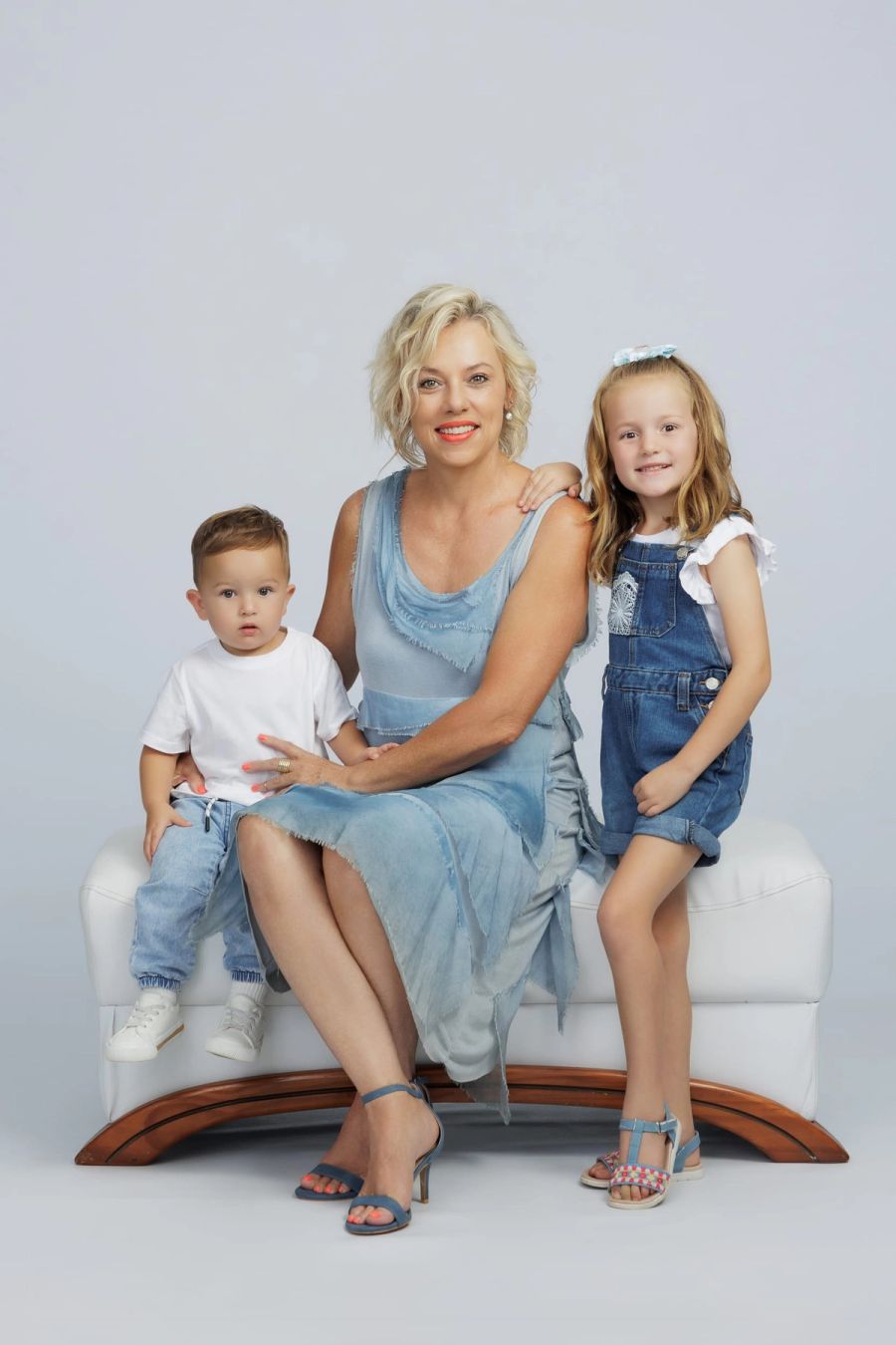 Mother with her young son and daughter seated on a white studio bench against a soft grey backdrop, Studio 039, Sea Park.