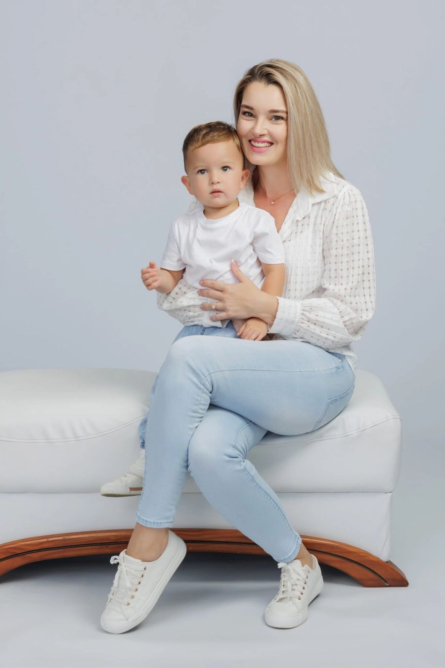 Mother holding her toddler son on her lap on a white studio bench against a soft grey backdrop, Studio 039, Sea Park.
