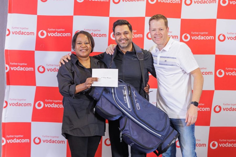 Vodacom staff golf day winner receiving a new golf bag and prize envelope in front of a branded Vodacom backdrop at San Lameer.