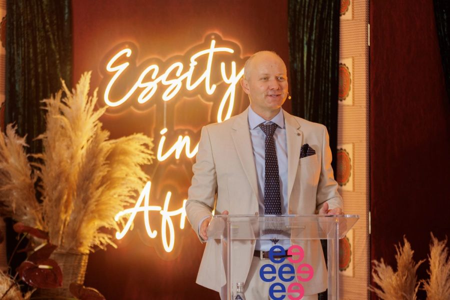 Speaker at a lectern in front of a glowing neon Essity in Africa sign at the Essity gala evening, Hoedspruit.