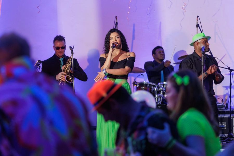 Live band with a singer and saxophonist performing for dancing guests under purple party lights, Pumula Hotel.