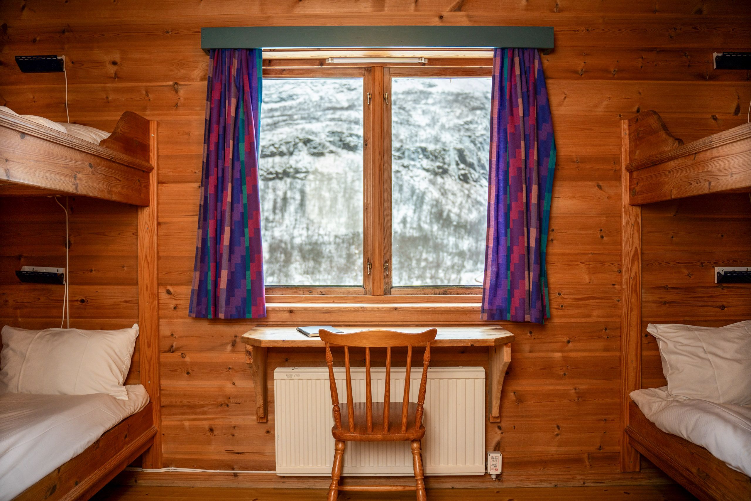 Arctic Coliving - photo of a cozy mountain bunk room with views of the mountains covered in snow in the distance
