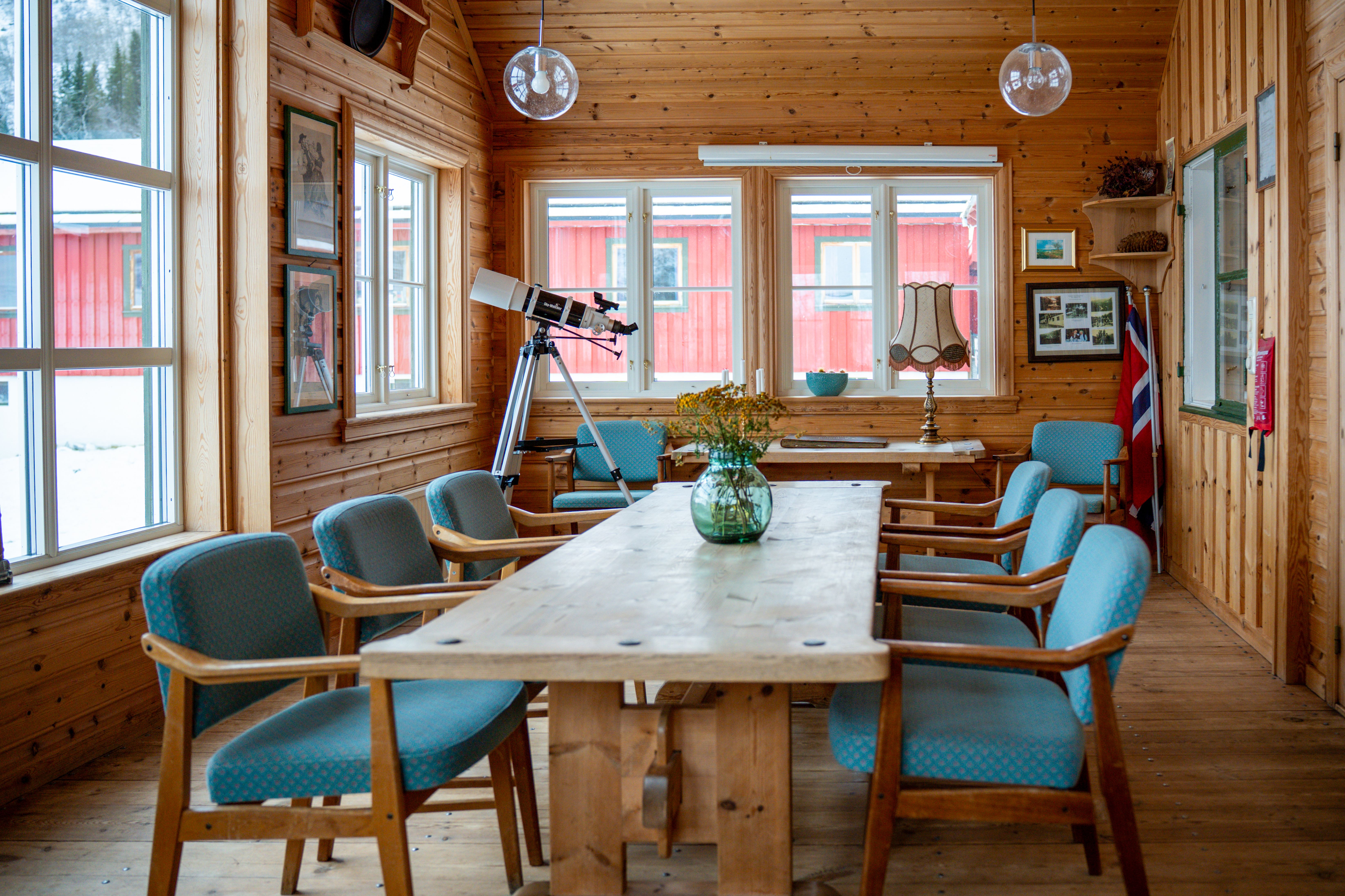 A light and airy room with wood walls and a long wooden table and chairs