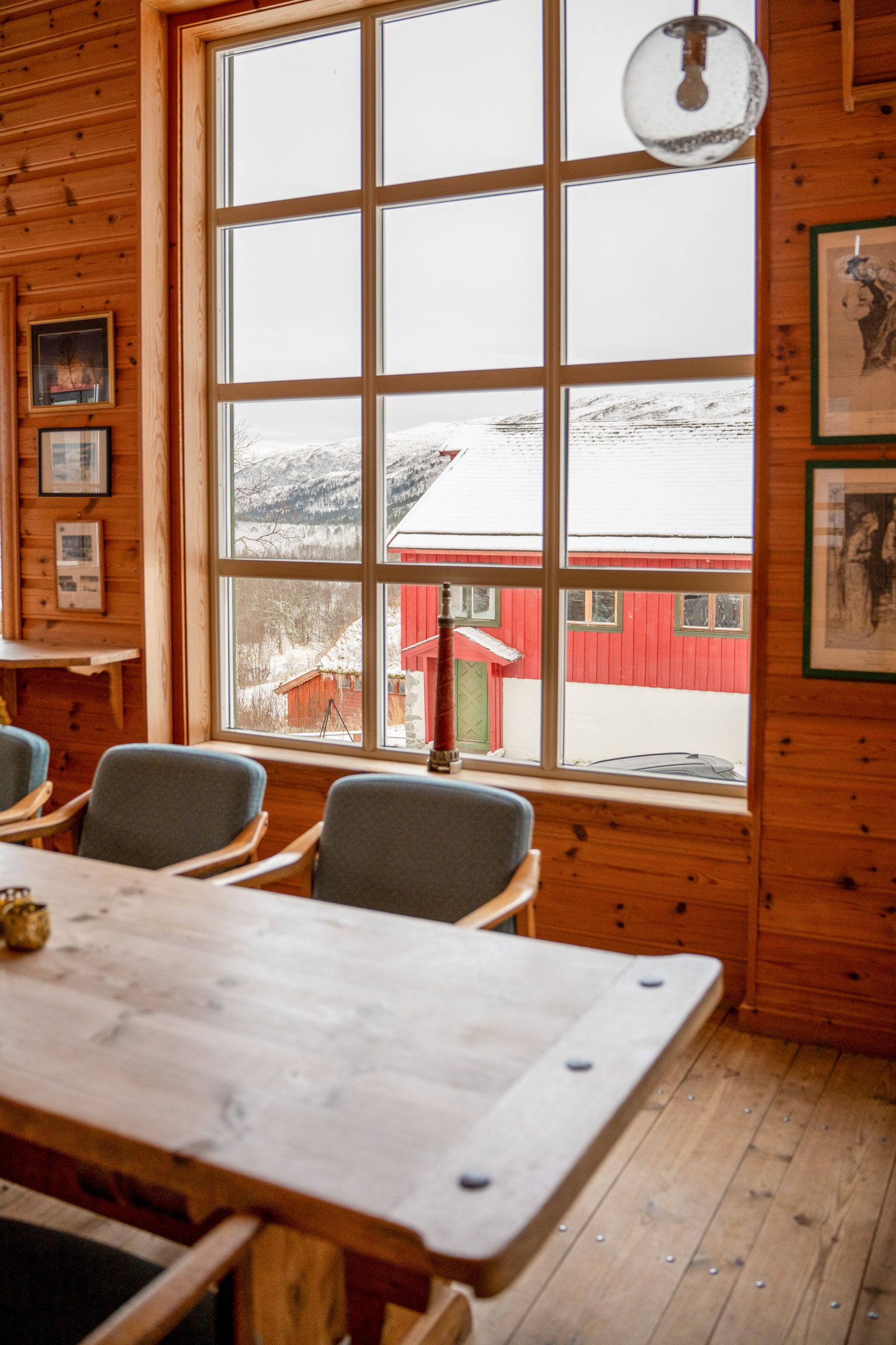 Arctic Coliving - a view of a wood panelled mountain lodge board room with winter views over the valley covered in snow