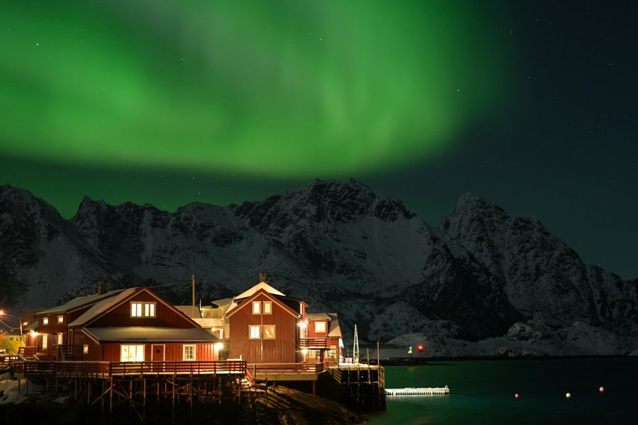 Northern lights over a red pier on the waterfront in Henningsvær in Lofoten, Norway