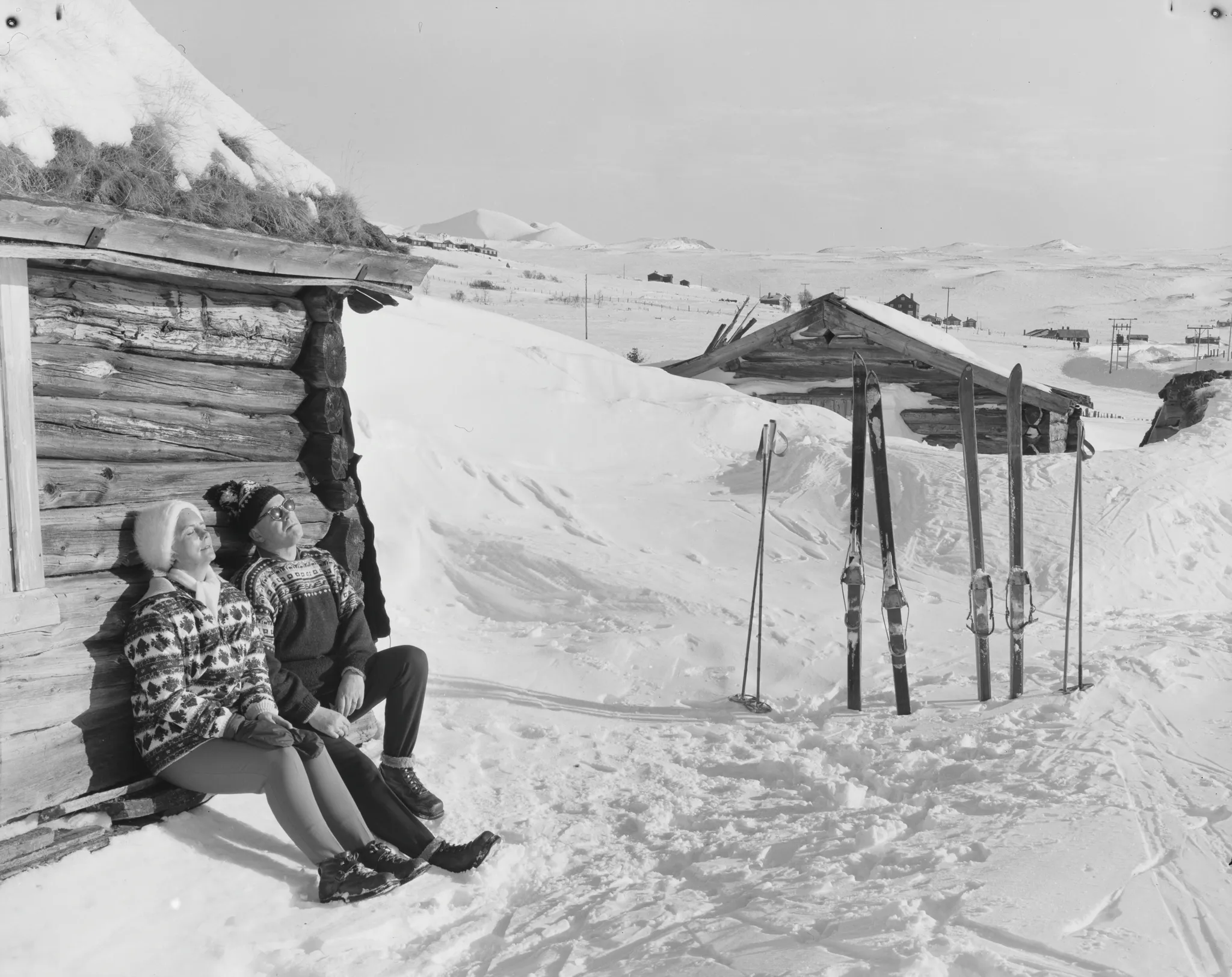 A black and white vintage photo of two skiers relaxing in the mountains