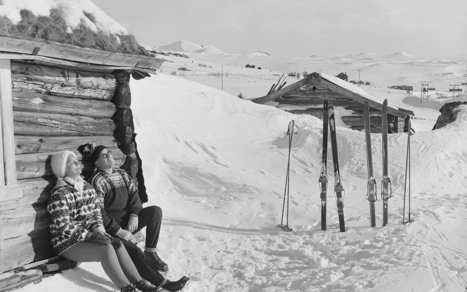 A black and white vintage photo of two skiers relaxing in the mountains