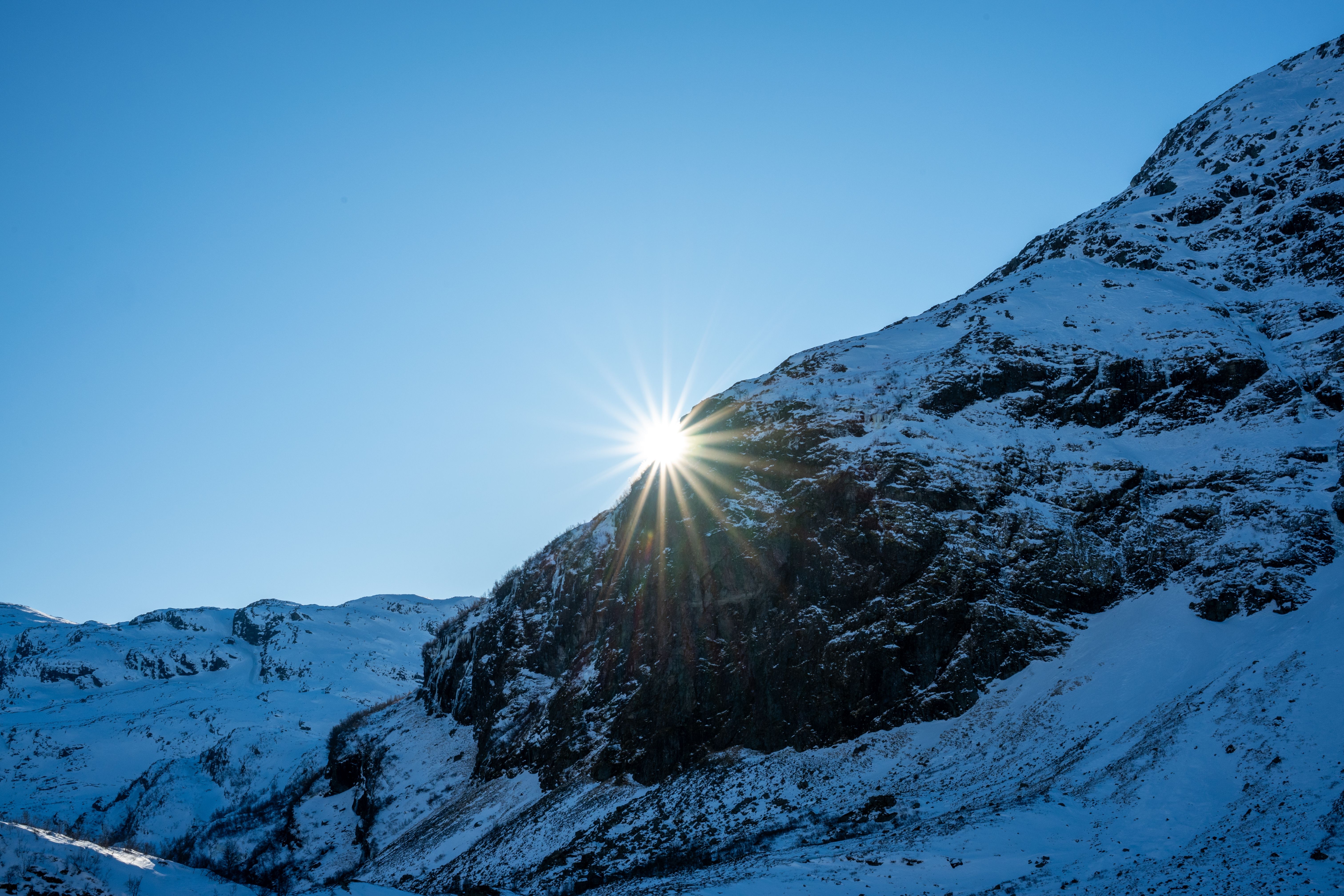 Bright sunburst over snow-covered mountains outside of Voss, Norway.