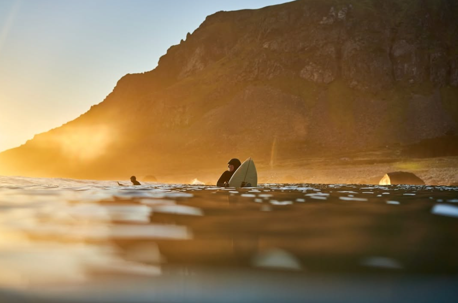 Surfers at sunset in Unstad beach in Lofoten 