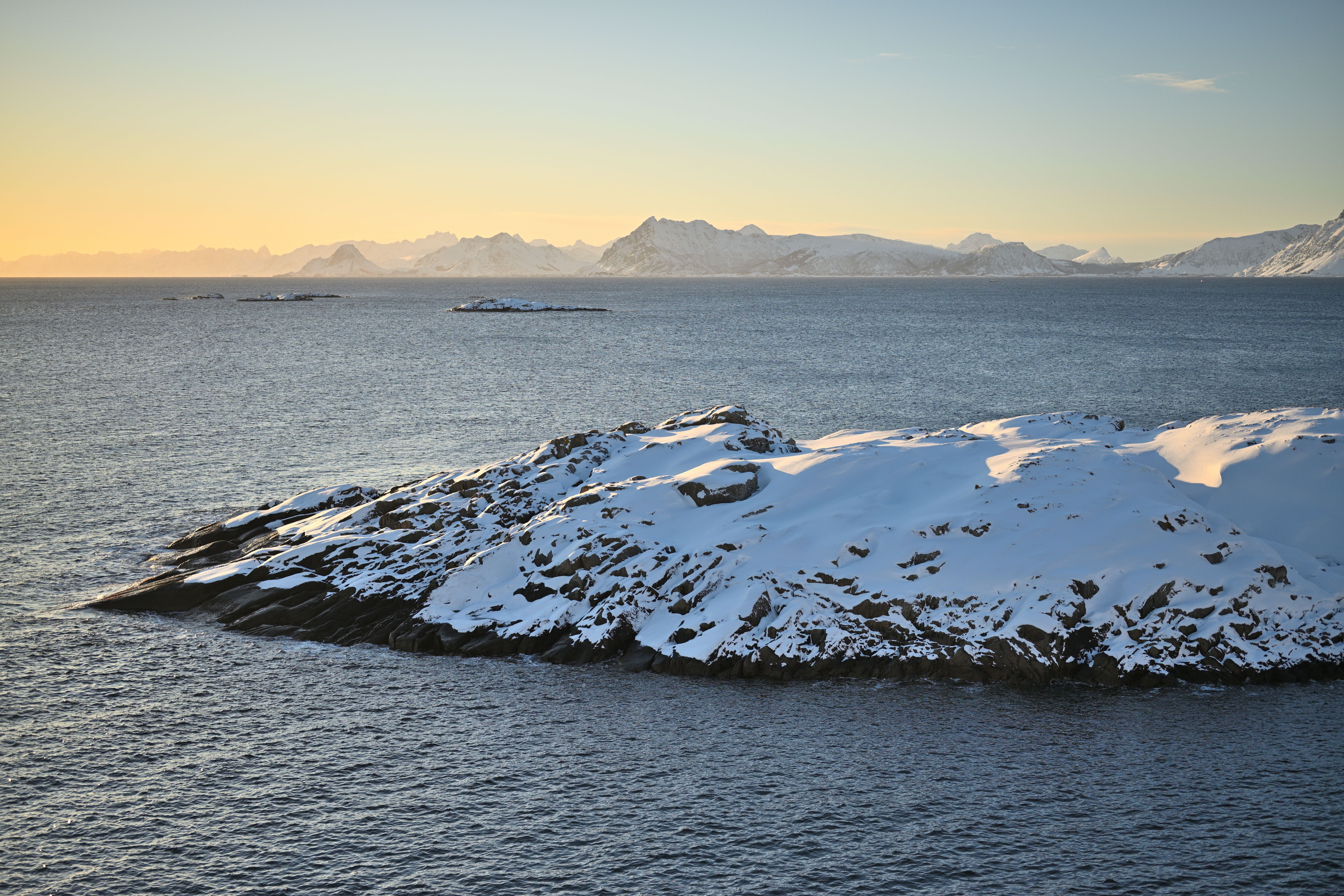 Mountains framing the snow covered coast at sunset in the northern Arctic archipelago of Lofoten Norway