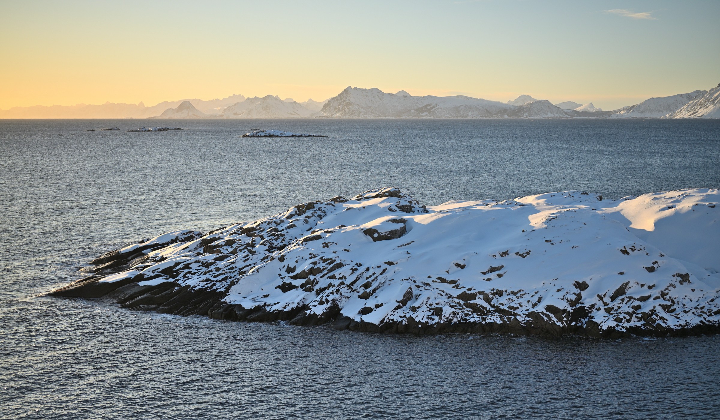 Snow-covered mountains rising across the Arctic Ocean in Lofoten, Norway, in February light.