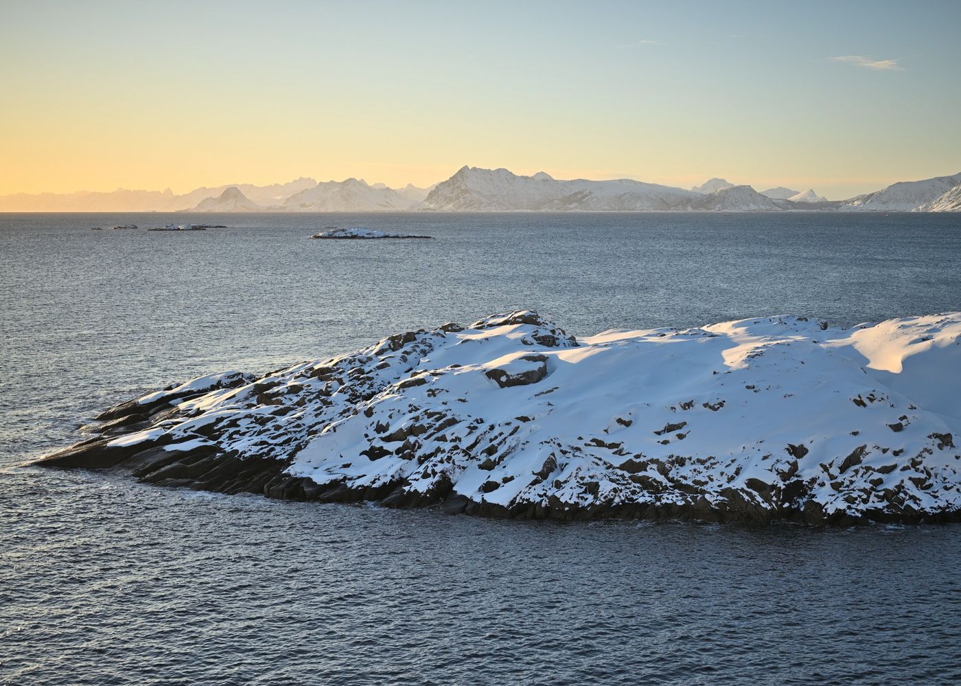 Mountains framing the snow covered coast at sunset in the northern Arctic archipelago of Lofoten Norway