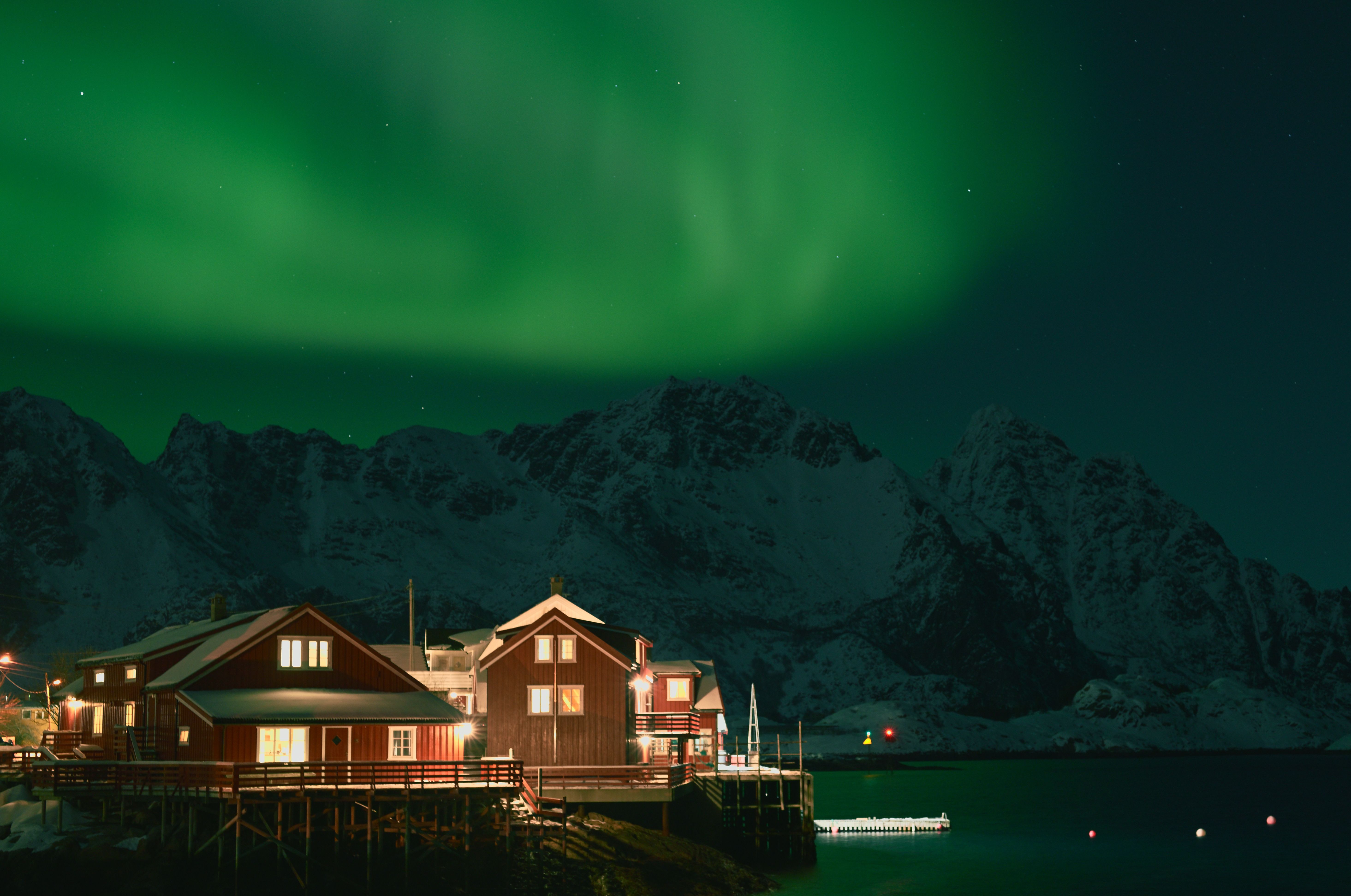A photo of a waterfront fishermen's cabins under the northern lights in Henningsvær Norway