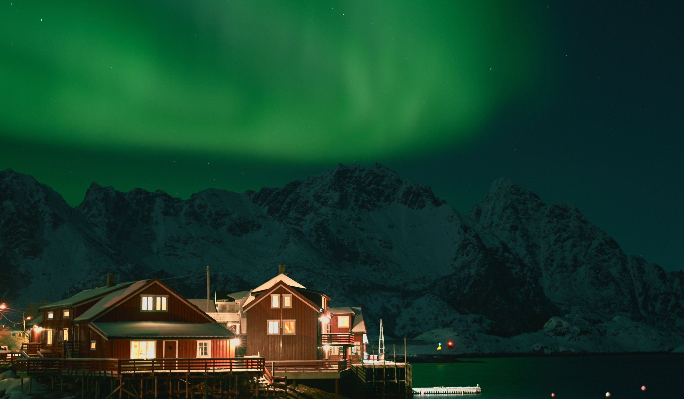 A photo of a waterfront fishermen's cabins under the northern lights in Henningsvær Norway