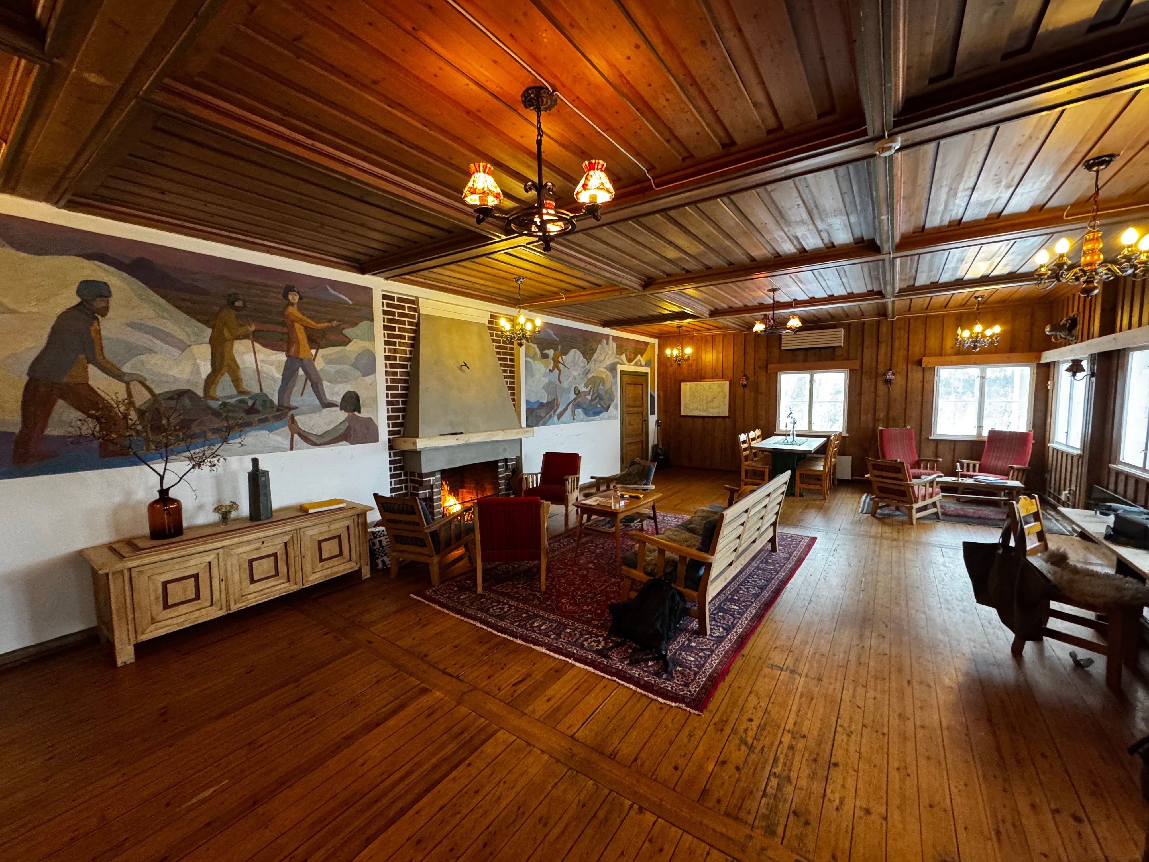 The living room and fireplace at Voss Mountain Lodge, with murals of Fridtjof Nansen.