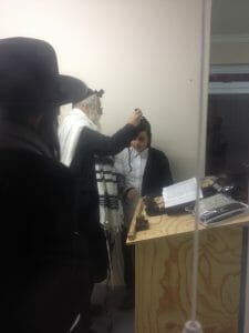 Rav Berland putting tfillin on a Bar Mitzvah boy now in South Africa