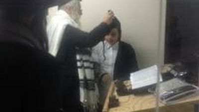 Rav Berland putting tfillin on a Bar Mitzvah boy now in South Africa