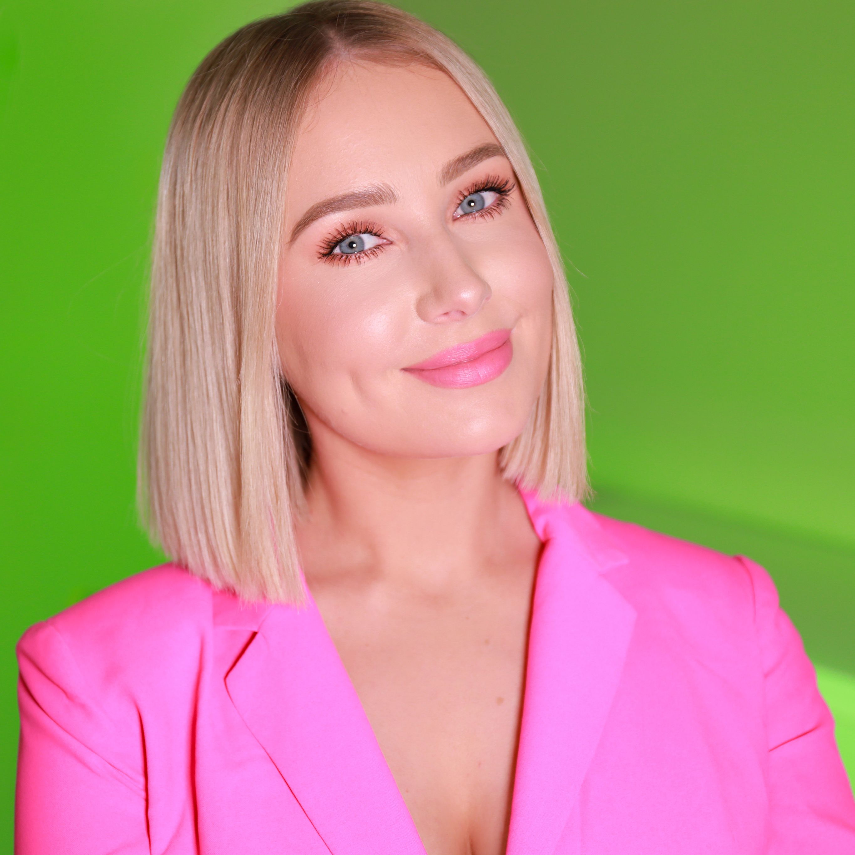 Portrait of Lauren Curtis wearing a pink blazer in front of a green background