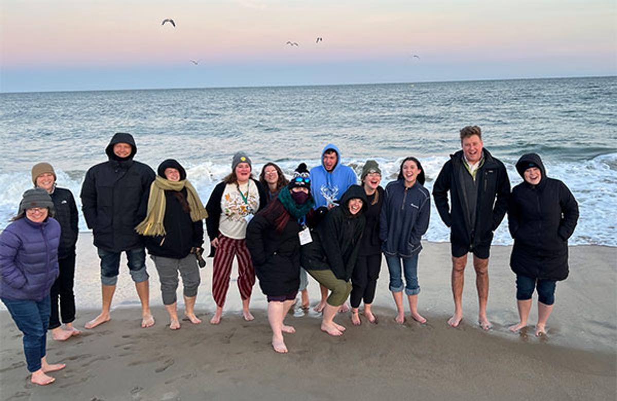 group of people posing for a photo in front of the ocean