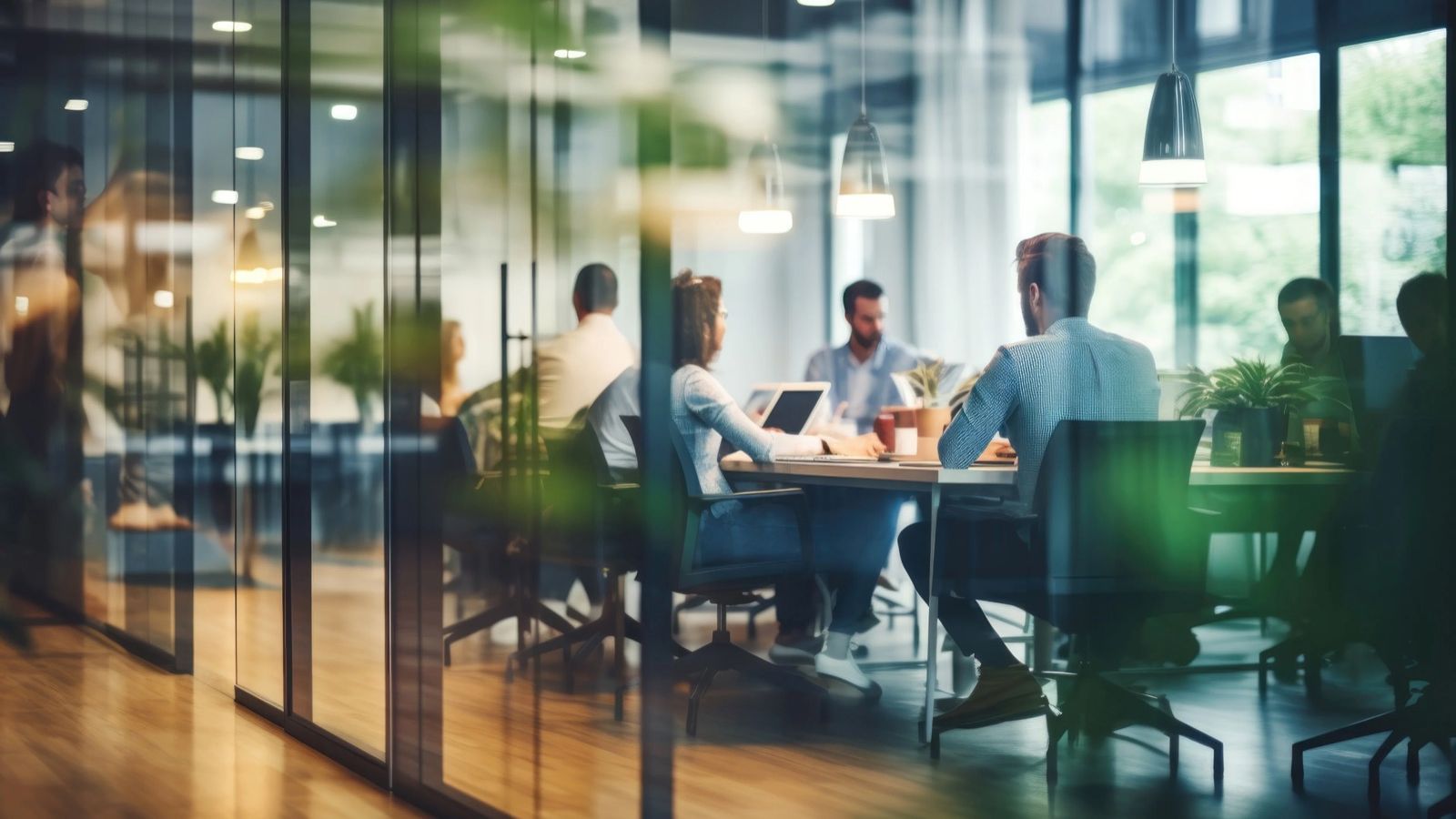 A team meeting round a table, seen through a glass office wall