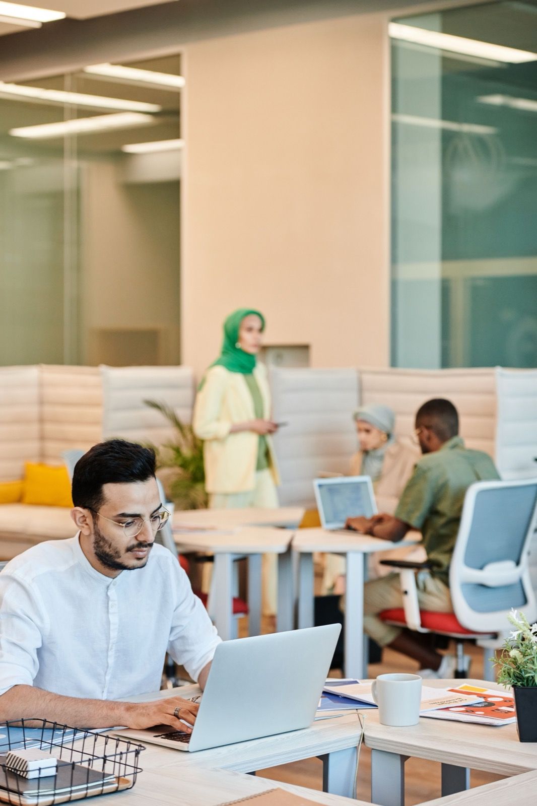 A man working on a laptop in a busy open-plan office