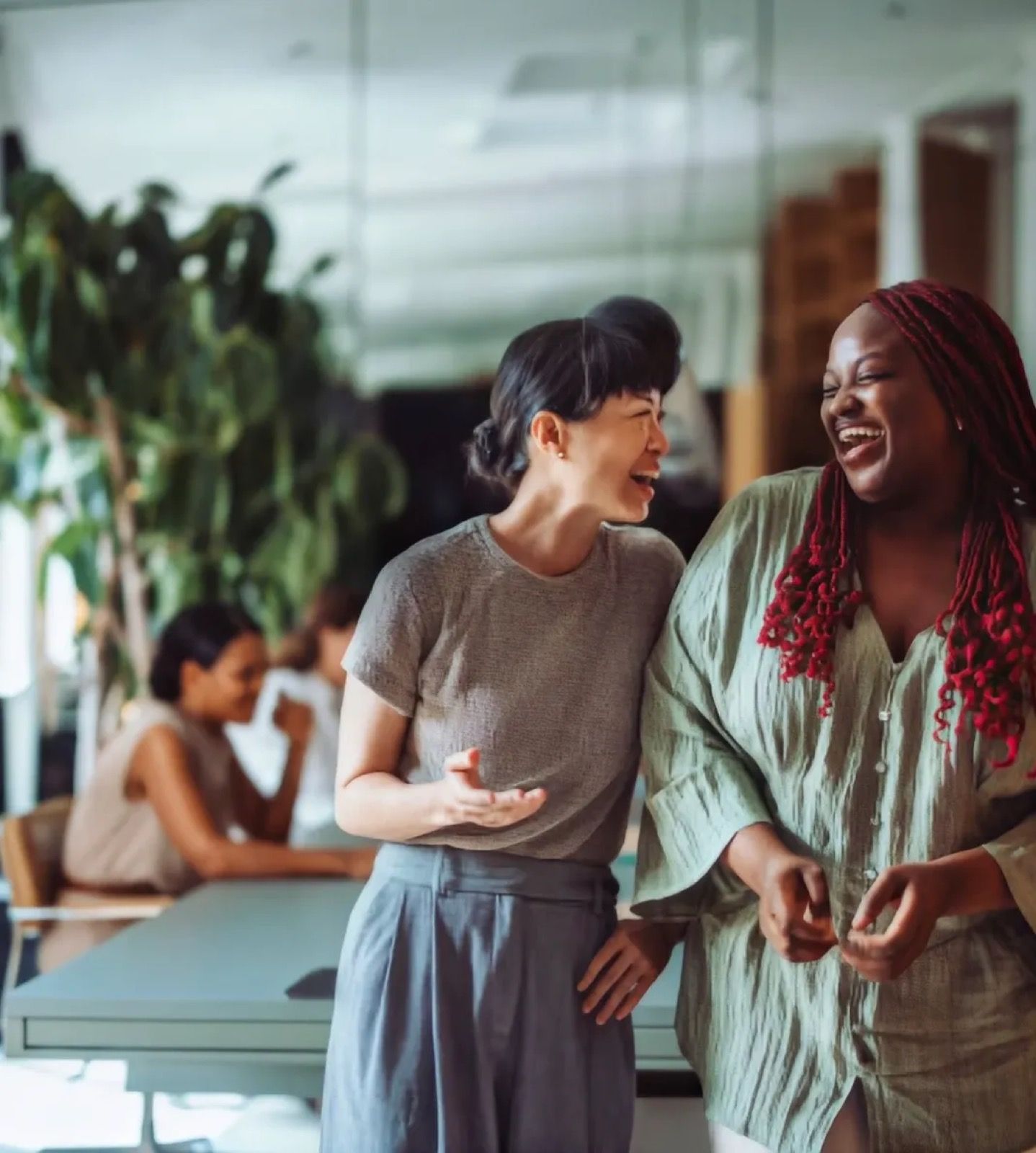 Two colleagues laughing as they walk through the office