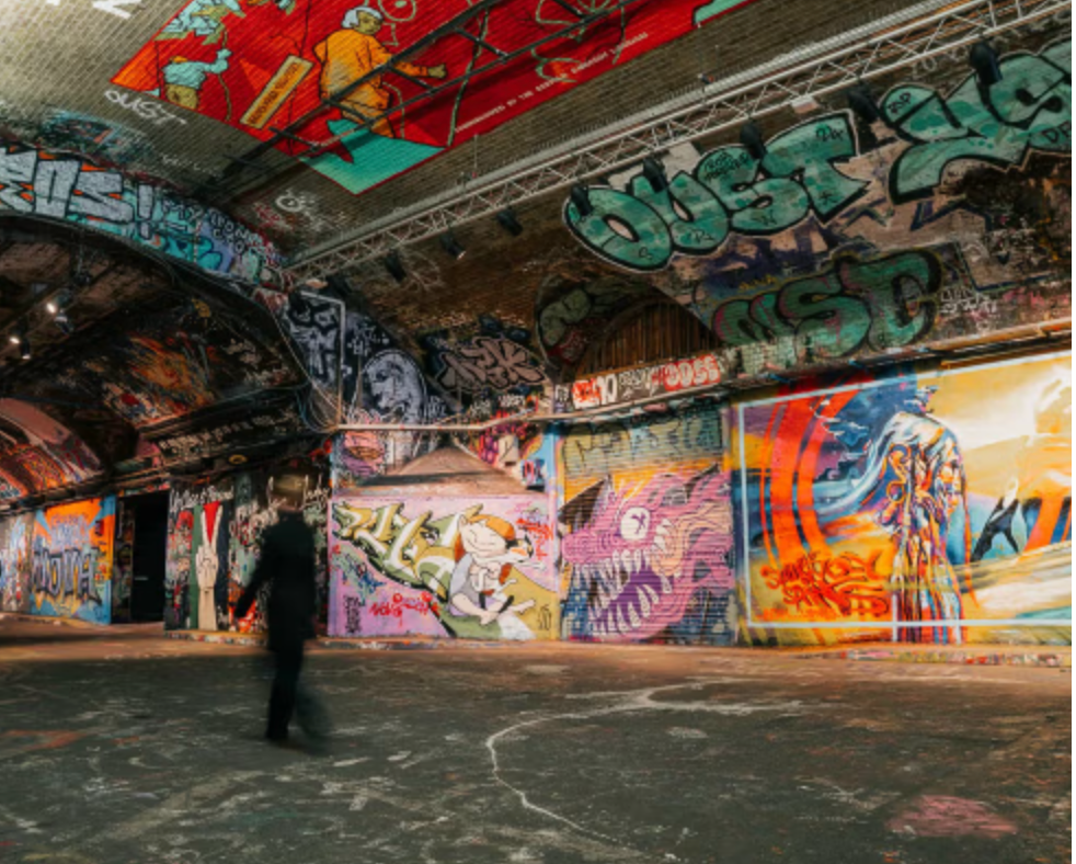 Newyork sttyle ware house space with tall arched ceig , exposed brick work and graffiti.