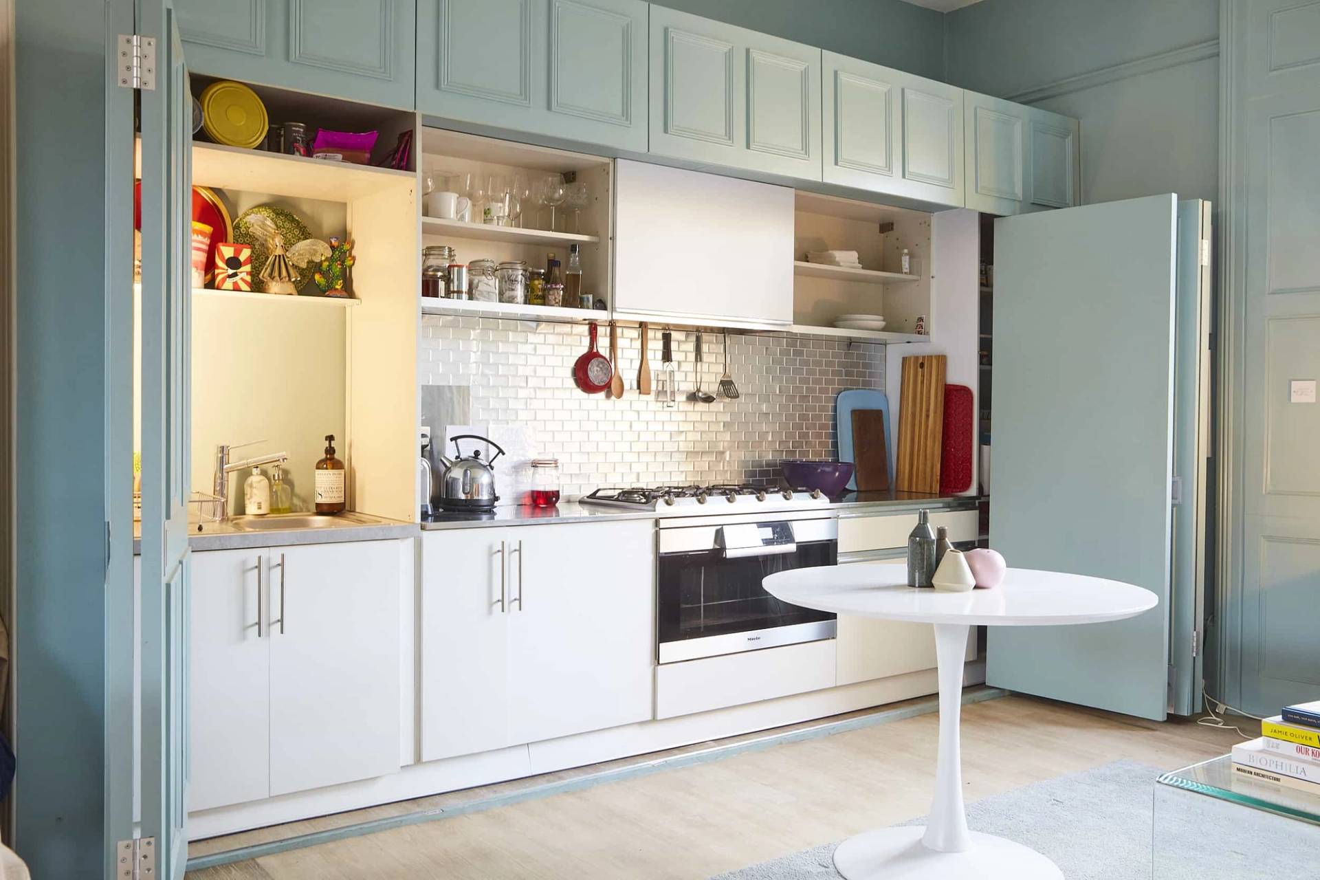 Built-in white kitchen unit hidden within a duck-egg blue panelled library room, ideal for food and beverage ads, Love Locations N5.